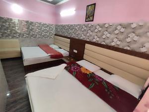 Vidya Guest House في كاترا: غرفة بسريرين وورود على الحائط