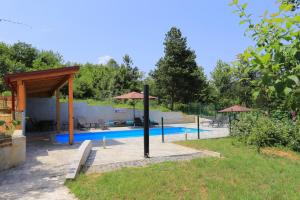 a swimming pool with umbrellas in a yard at Apartments and rooms with a swimming pool Grabovac, Plitvice - 17531 in Rakovica