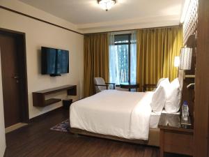 a hotel room with a bed and a television at Radisson Golf Resort Pahalgam in Pahalgām