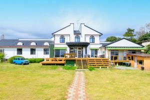 duży biały dom z ceglaną ścieżką w ogrodzie w obiekcie Guesthouse leaf w mieście Hokuto