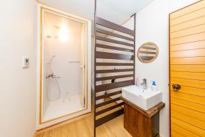 La salle de bains est pourvue d'un lavabo et d'une douche. dans l'établissement Guesthouse leaf, à Hokuto