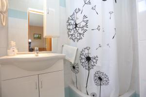 a bathroom with a sink and a shower curtain with flowers at Rooms with a parking space Grabovac, Plitvice - 17419 in Rakovica