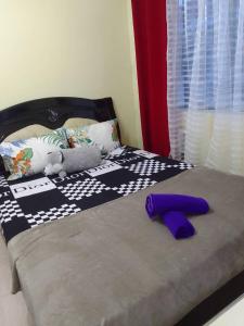 uma cama com um edredão preto e branco e almofadas roxas em Affordable Condo for Rent in Valley Mansions em Cainta