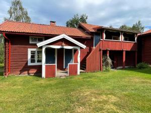 una casa roja con la puerta abierta en un patio en Dalastuga med tillgång till badplats, en Leksand