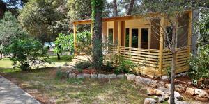 a yellow tiny house in the woods at Camping Kozarica Mobile Homes in Pakoštane