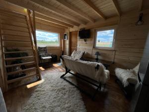 una sala de estar con sofá en una cabaña de madera en Domek wypoczynkowy - Stajnia Magenta 