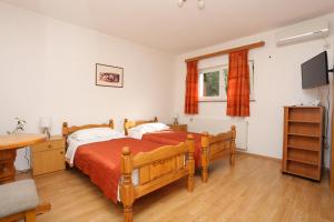 斯盧尼的住宿－Rooms with a parking space Slunj, Plitvice - 17485，一间卧室配有两张床、一张桌子和一台电视。