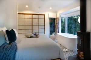 a bedroom with a large bed and a bath tub at Lovestone Cottages Montville in Montville