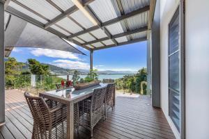 a patio with a table and chairs on a deck at MANDALAY ESCAPE, SECLUSION & SERENITY WITH A POOL in Airlie Beach