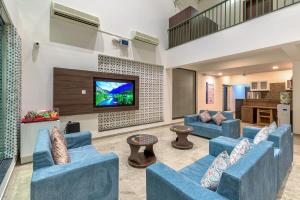 a living room with blue couches and a flat screen tv at SaffronStays Amaltas, Nashik - pool villa with huge lawns perfect for large groups and corporate offsites in Nashik