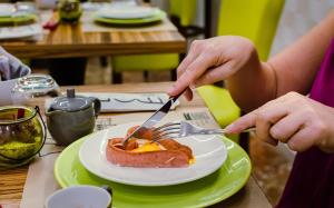 una persona che tiene in mano una forchetta, un coltello e un piatto di cibo di B&B Vanity a Tropea