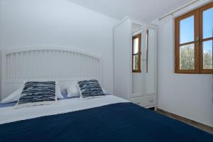 een witte slaapkamer met een bed met blauwe lakens en kussens bij Holiday house with a parking space Pitve, Hvar - 17397 in Jelsa