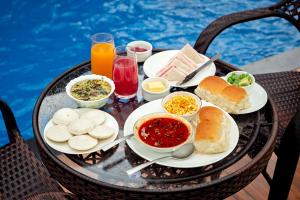 a table with plates of food and drinks and a pool at SaffronStays Amaltas, Nashik - pool villa with huge lawns perfect for large groups and corporate offsites in Nashik