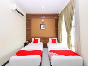 two beds in a hotel room with red pillows at Super OYO Capital O 812 Hotel SMC Seksyen 13 in Shah Alam