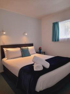 a bedroom with a large bed with two towels on it at Marlin Court Motel in Paihia