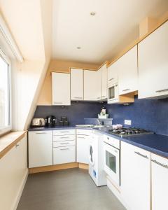 a kitchen with white cabinets and a blue wall at Amazing Castle View Apartment in Edinburgh