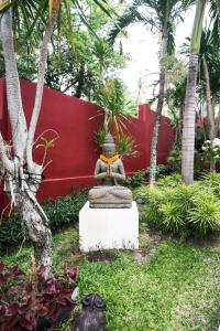 een standbeeld in een tuin voor een rode muur bij CASA MIMBA - Seaview Private Pool Villa Padangbai in Padangbai