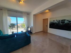 - un salon avec un canapé bleu et une grande fenêtre dans l'établissement Sea View Apartment, à Cap Sounion