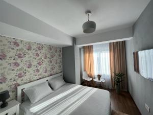 1 dormitorio con 1 cama y papel pintado con motivos florales en Ballade Apartment, en Iaşi