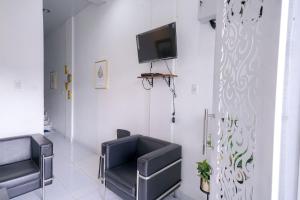 a waiting room with two chairs and a tv on the wall at RedDoorz near Pantai Pandan Sibolga in Halangan