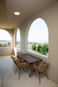 een eetkamer met twee gewelfde ramen en een houten tafel en stoelen bij Olive Villa in Kamari