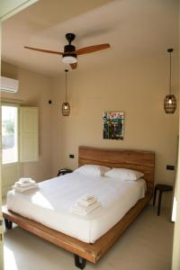 a bedroom with a bed with white sheets and a ceiling fan at Olive Villa in Kamari