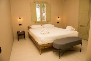 um quarto com uma cama com lençóis brancos e uma cadeira em Olive Villa em Kamari