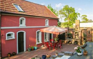 een rood huis met een tafel en stoelen en een paraplu bij Amazing Home In Nowe Warpno With Kitchen in Nowe Warpno