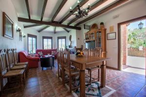 uma cozinha e sala de estar com uma mesa de madeira e cadeiras em Casa Mirador Las claras Con Piscina privada jardin y AireAcodicionado em Iznate