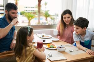 a family sitting at a table with plates of food at Iberostar Playa Gaviotas Park-All inclusive in Morro del Jable