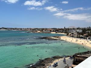 a beach with people swimming in the water at Pearl Apartment Corralejo in Corralejo