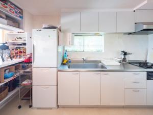 a white kitchen with a sink and a refrigerator at Villa LIGHT HOUSE -館山 LIGHT HOUSE- ペット可 in Susaki