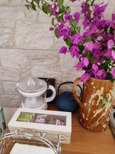 een boek en een vaas met paarse bloemen op een tafel bij Casedda Ostunese in Ostuni