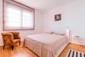 ein Schlafzimmer mit einem Bett, einem Stuhl und einem Fenster in der Unterkunft Apartments with a parking space Medulin - 17107 in Medulin