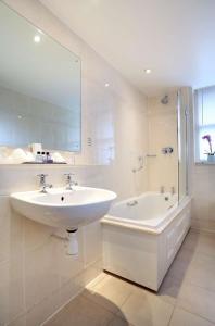 a white bathroom with a sink and a bath tub at Macdonald New Blossoms Hotel in Chester