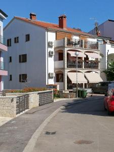 um edifício branco com uma varanda e um parque de estacionamento em Apartment Vrsar 17473b em Vrsar