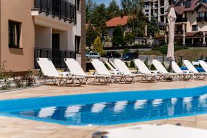 a row of lounge chairs next to a swimming pool at Monix Palace Zlatibor in Zlatibor