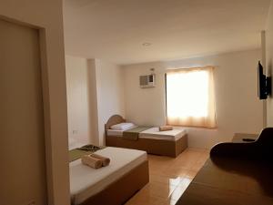 パングラオにあるAlona Guest Houseのベッド2台と窓が備わる小さな客室です。