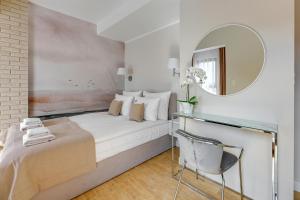 een slaapkamer met een bed, een spiegel en een stoel bij Aura III Apartments & Free Parking by Downtown Apartments in Gdańsk