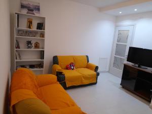 uma sala de estar com um sofá amarelo e uma televisão em Anna's house Su Planu em Cagliari