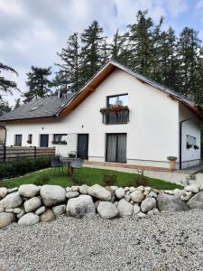 una casa blanca con un montón de rocas delante de ella en Apartmány Runi en Stará Lesná