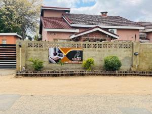 a fence in front of a house with a sign on it at Abrama Bed And Breakfast in Francistown