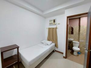 um quarto branco com uma cama e um WC em Island Hop Inn em El Nido