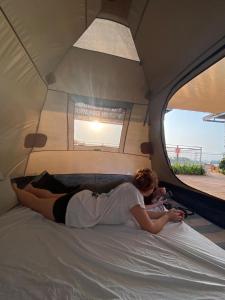 zwei Frauen auf einem Bett in einem Zelt in der Unterkunft Atlit Rooftop Glamping in Atlit