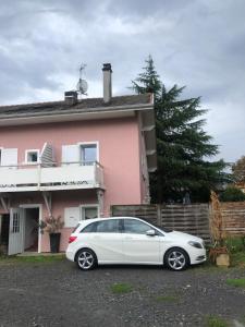 un coche blanco estacionado frente a una casa rosa en studio 6 Versoie avec parking, en Thonon-les-Bains