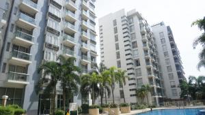 dois edifícios altos com palmeiras em frente a uma piscina em Palm Tree Villas Condominium by Beth em Manila