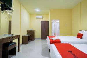 um quarto de hotel com duas camas e uma secretária em RedDoorz Plus @ Jalan FL Lumban Tobing Sibolga em Sibolga