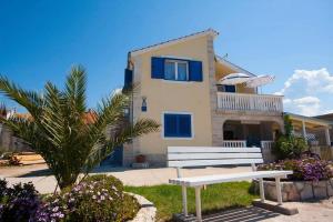 a white bench in front of a house at Family friendly seaside apartments Krapanj, Sibenik - 18004 in Šibenik