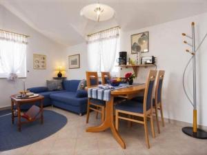 ein Wohnzimmer mit einem Tisch und einem blauen Sofa in der Unterkunft Family friendly seaside apartments Krapanj, Sibenik - 18004 in Šibenik