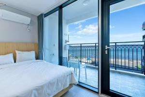 a bedroom with a bed and a balcony at Gold Beach Resort in Yeosu